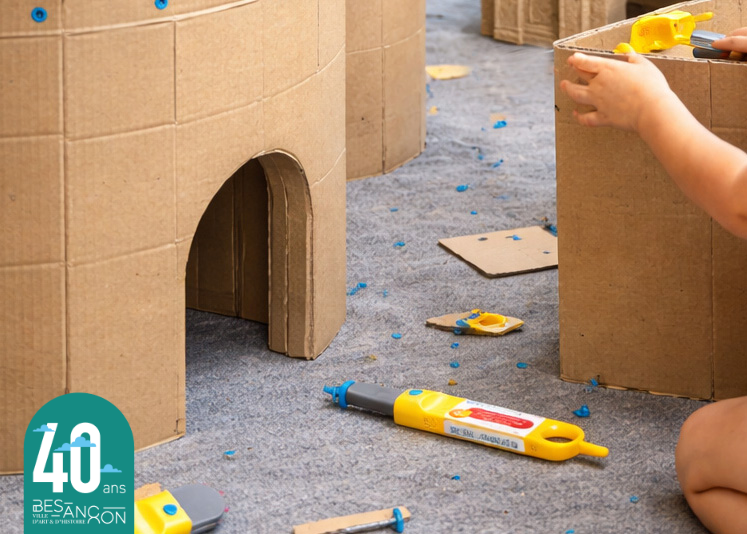photographie de mains d'enfant en train de réaliser une maquette en carton grand format