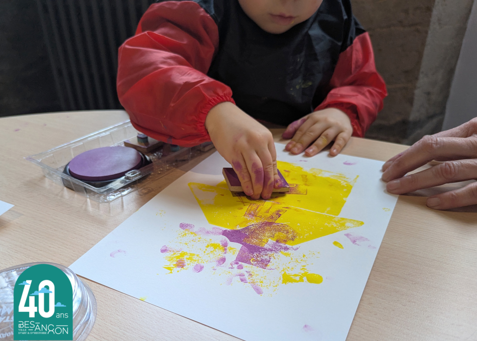photographie d'un enfant où l'on voit ses mains tamponner sur une feuille en papier