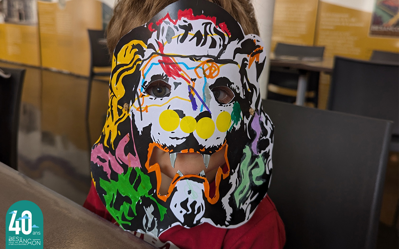 un enfant porte un masque de monstre colorié par lui même